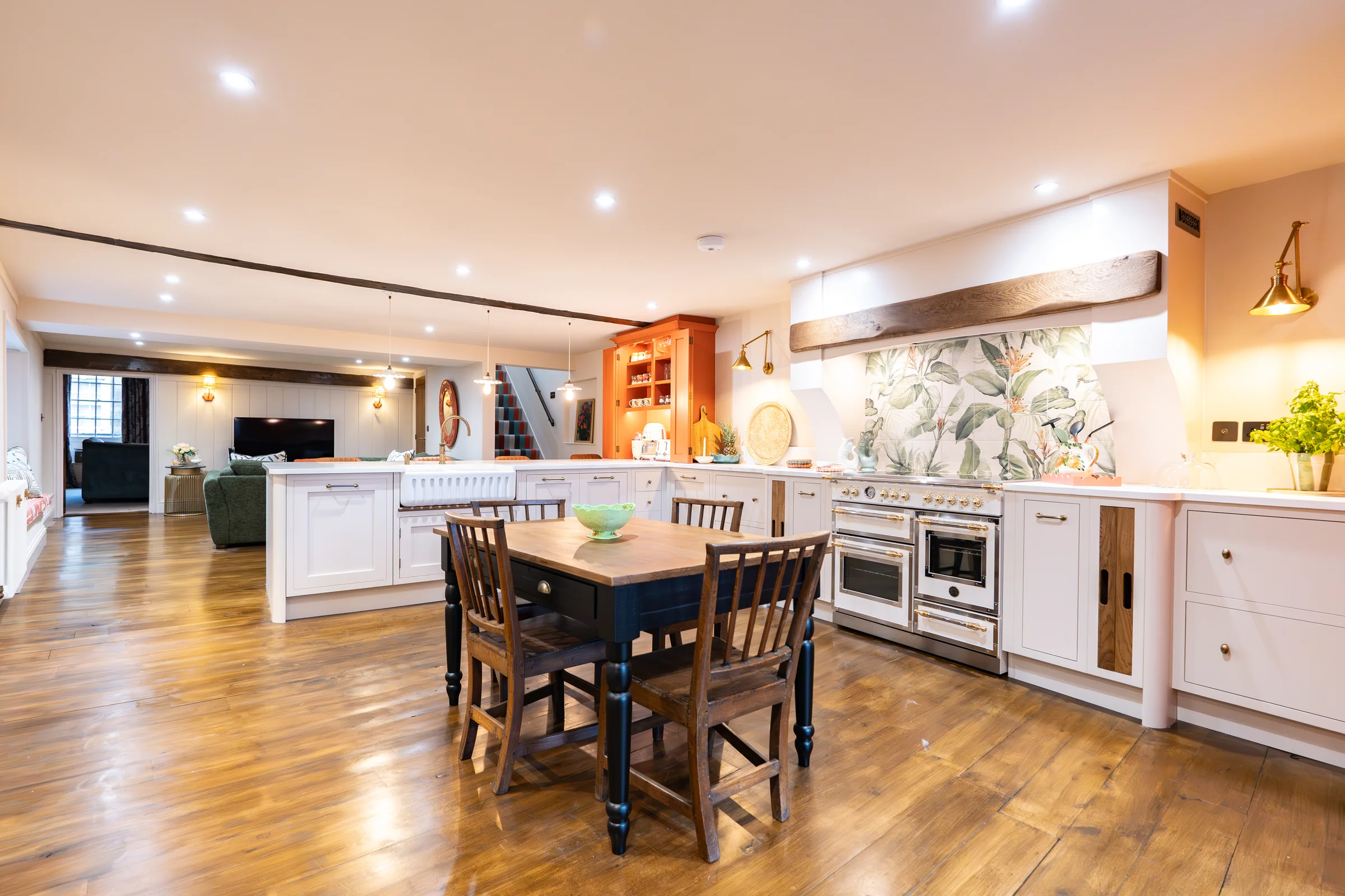 Open plan kitchen white shaker bertazzoni range botanical splashback beam orange dresser oak floor